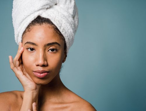calm young ethnic woman with perfect skin touching face after shower