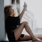 woman in black dress sitting on window