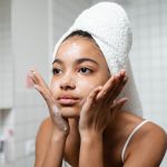 woman in white tank top washing her face with soap